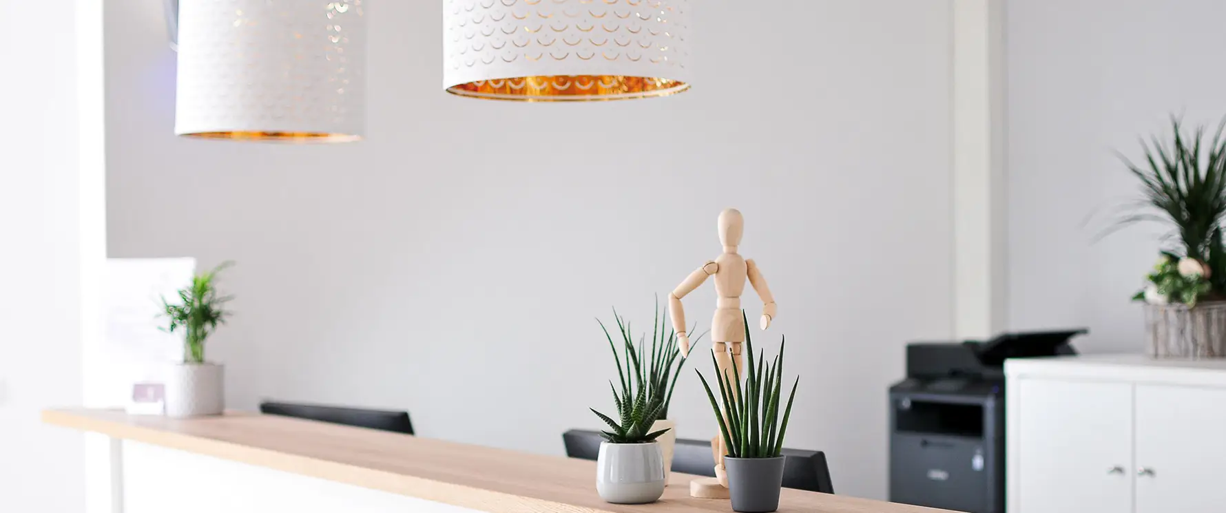 Empfangsbereich der Praxis Gelenkich mit Tresen, Pflanzen und anatomischer Holzfigur.